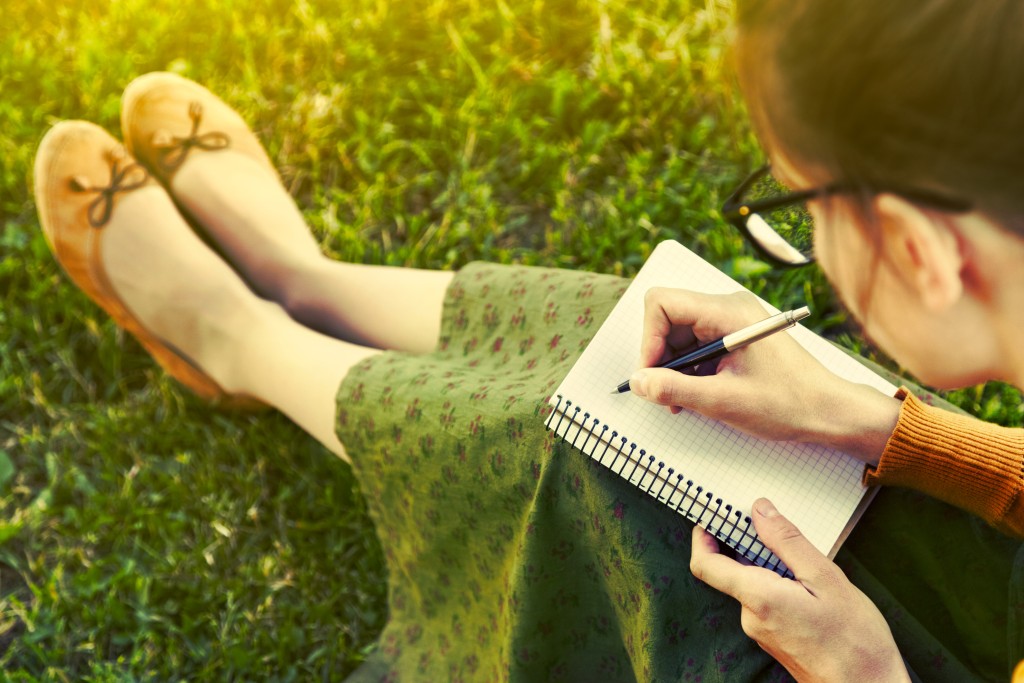 Woman writing in journal on lawn