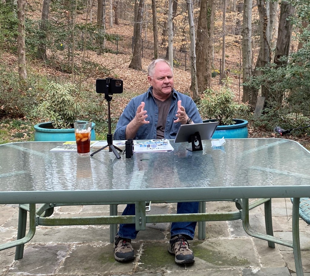 Man working at this outdoor office with forested woodlot in background.