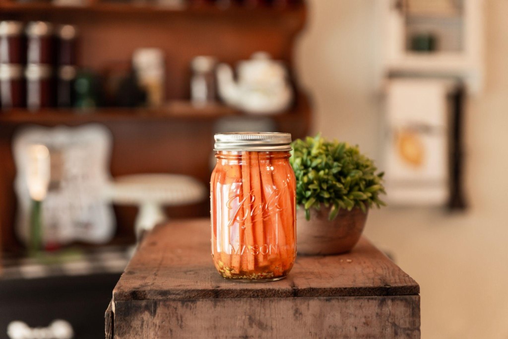 Mason jar of carrot sticks on a wooden counter.
