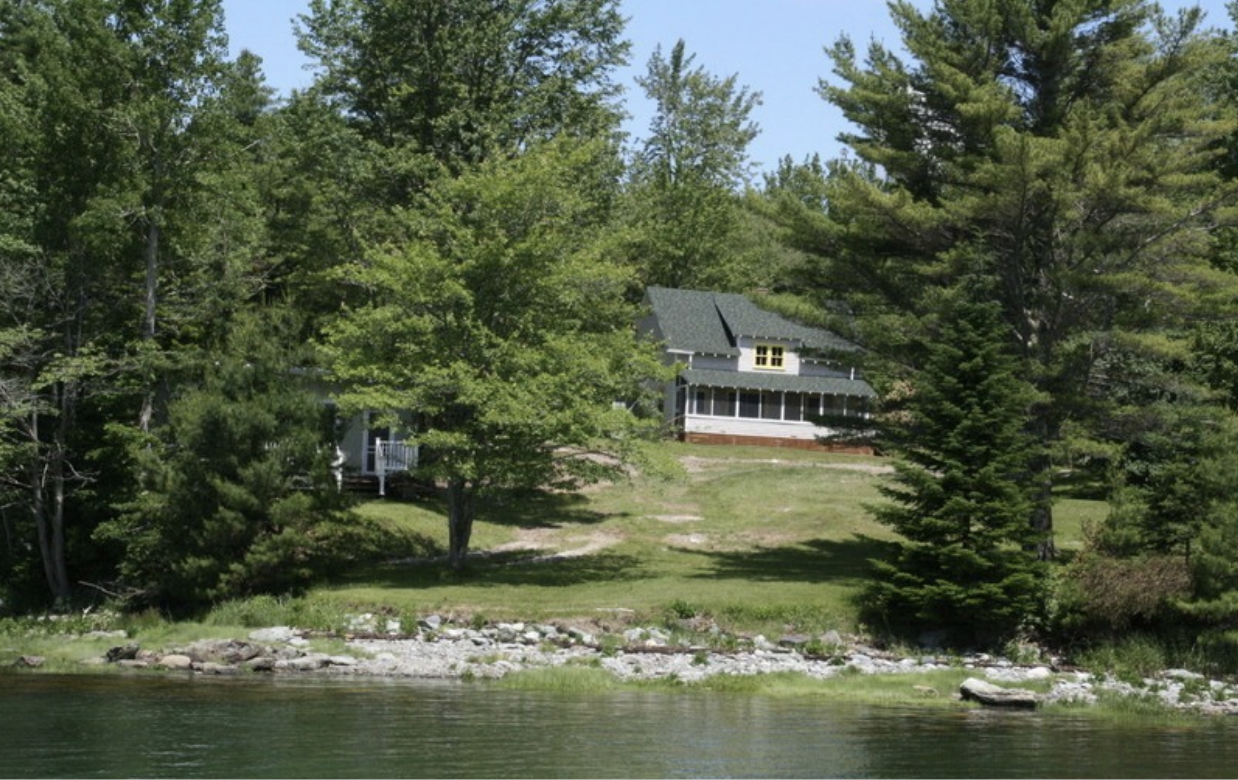 Summer cottage on lake with big lawn.