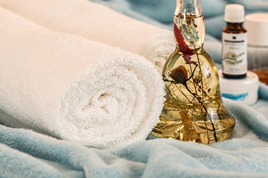 Home-made facial oil made from garden herbs, white towel.
